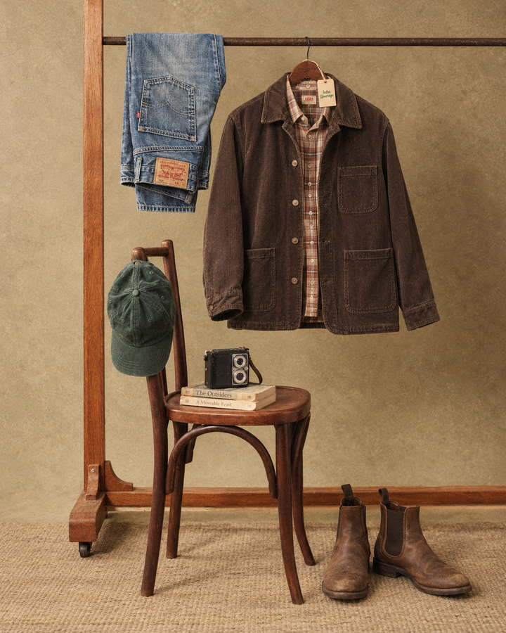 Inspirație Vintage: jachetă din catifea reiată, cămașă în carouri și denim, alături de un scaun vechi și aparat foto.